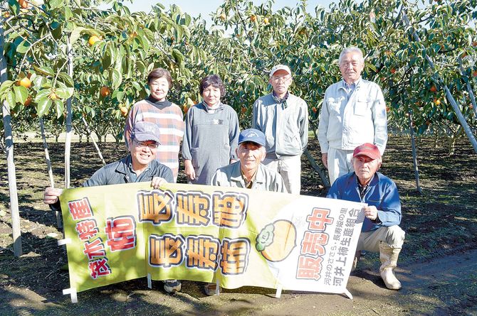 自然豊かな里山の柿畑で笑顔を見せる組合員たち