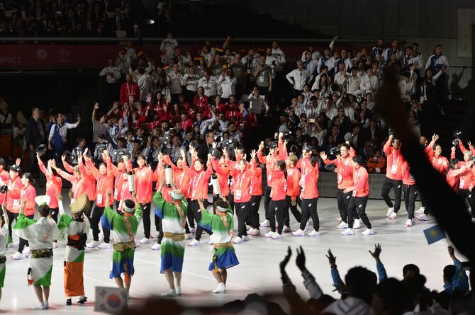 客席から手話の拍手で迎えられる日本選手団＝１５日午後、東京体育館