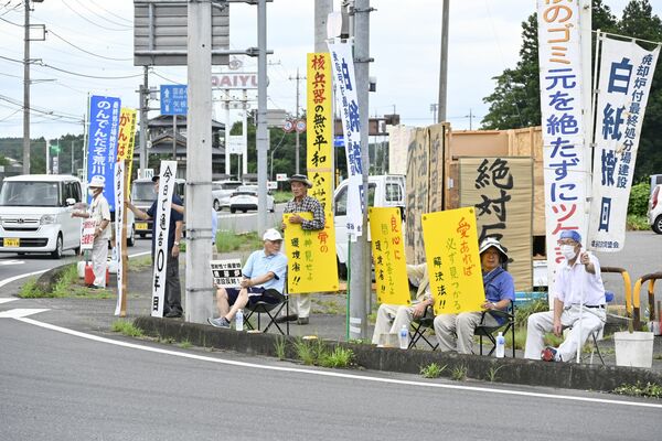 手作りの看板を持ち候補地の白紙撤回を訴える町民ら＝30日午前８時40分、塩谷町玉生