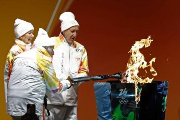 コルティナダンペッツォで行われたミラノ・コルティナ冬季五輪の聖火リレーに参加したランナーのマヌエラ・アンジェリさん(左)ら=26日(共同)