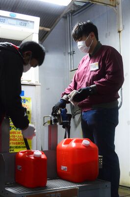 灯油を販売するホームセンターの店員。順番待ちの列もできた＝23日午後５時15分、宇都宮市西川田本町２丁目