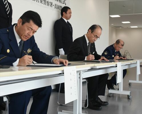 覚書に署名する高井社長（中央）と宇都宮東署の篠原署長（手前）、真岡署の生井署長＝29日午前、宇都宮市下平出町
