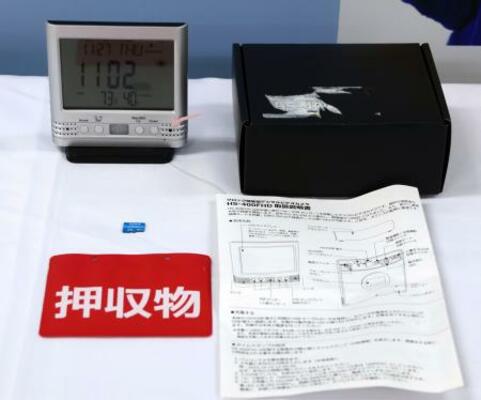 デジタル時計型の小型カメラ(左上)などの押収物=27日午前、愛知県警本部