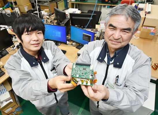 キューブサットに搭載する電源ユニットを手にする開発責任者の岡本さん（右）と末永さん