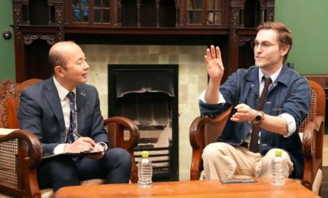 　長崎市の鈴木史朗市長（左）と対談するクレイグ・モドさん＝１９日午後、長崎市