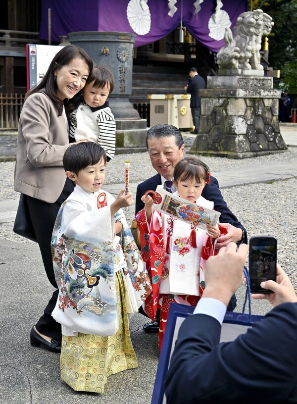 晴れ着姿で千歳飴を持って記念撮影をする家族連れ＝３日午前10時15分、宇都宮市馬場通り１丁目