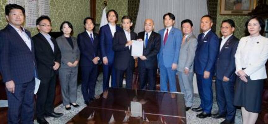 選挙運動に関するSNS対策に向けた法改正案を衆院の築山信彦事務総長(中央右)に提出する与野党の議員ら=24日午後、国会