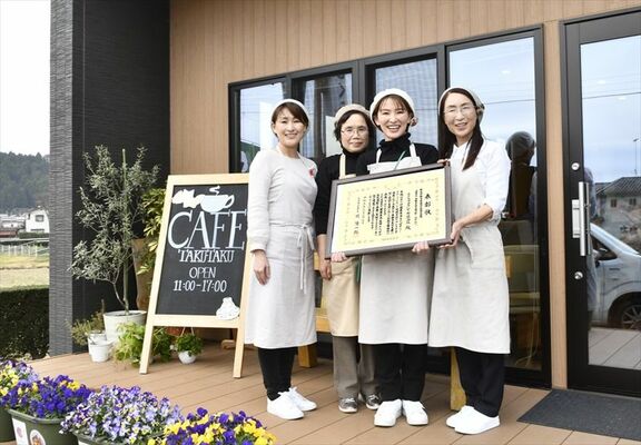 表彰状を手にカフェの前で笑顔を見せる横山さん（右から２人目）ら