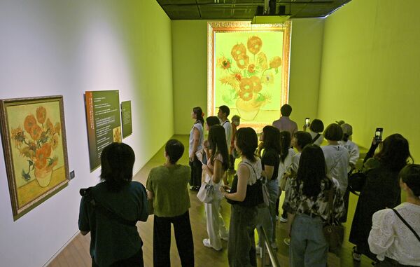 壁面に投影された「ひまわり」に見入る大勢の来館者たち=6日午前11時20分、宇都宮市桜4丁目