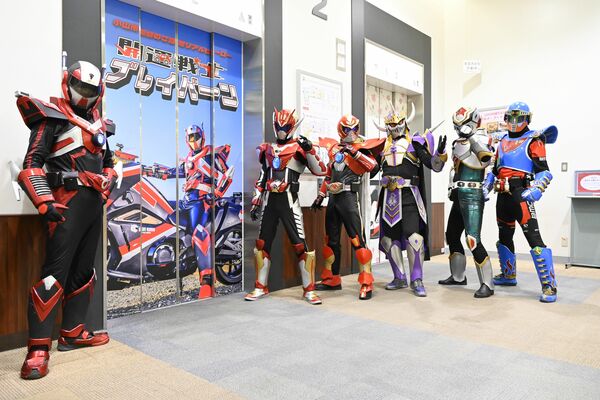 ラッピングされたエレベーターの前でポーズ
を決めるブレイバーン（左）