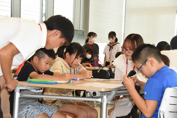 高校生、大学生に教わりながら勉強する児童