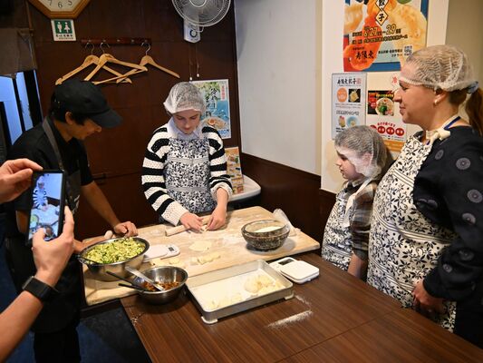 ギョーザ作りを体験する国際会議参加の外国人家族ら