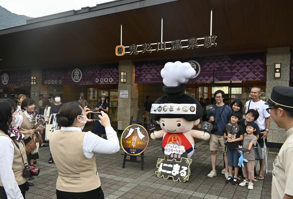 ８周年を記念し、鬼怒川温泉駅前に登場した「にこまる」と写真撮影する観光客ら
