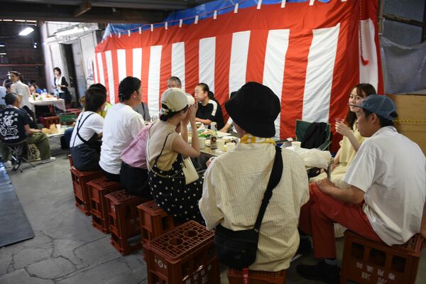 酒瓶ケースに座り、日本酒や料理を楽しむ参加者たち＝５月30日、栃木市