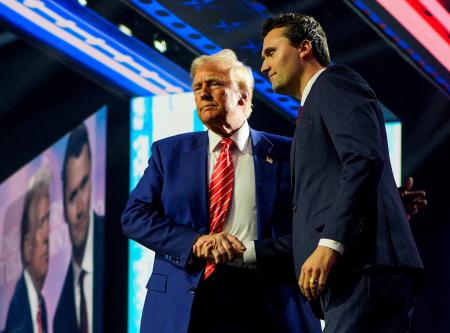 　大統領就任前のトランプ氏（左）と握手するチャーリー・カーク氏＝２０２４年１２月、米アリゾナ州（ロイター＝共同）