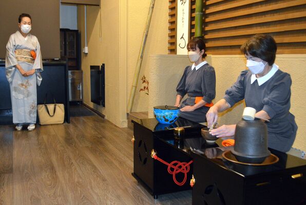 田村の茶わんで茶をたてるホテルスタッフと、茶道について解説する荒井さん（左）