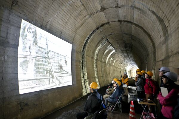 大峯山トンネル内に映し出された建設当時の映像に見入る参加者＝12日午後０時35分、茂木町小井戸