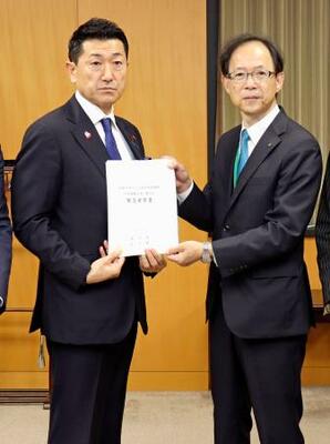 赤間二郎防災担当相(左)に要望書を手渡す大分県の佐藤樹一郎知事=27日午後、内閣府