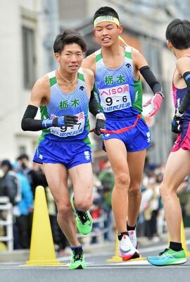 ６区の中村（右）からたすきを受け走り出す７区の菊地＝広島市内