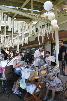 梨をイメージした飾り付けの下で、梨色の服を着てワークショップを楽しむ家族連れ