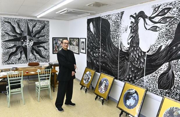 巨大木版画の鳳凰（右）と太陽（奥左）の前に立つ君島さん
