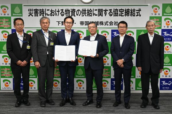 協定書を手にする坂村市長（左から３人目）と桝谷社長（同４人目）＝下野市役所