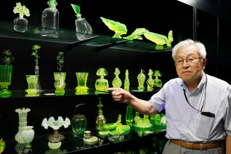 　国内外で収集したウランガラス作品を指さす新森慎之助さん＝２０２５年９月、富山県高岡市