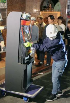 押収されるパチスロ機=24日、東京都新宿区
