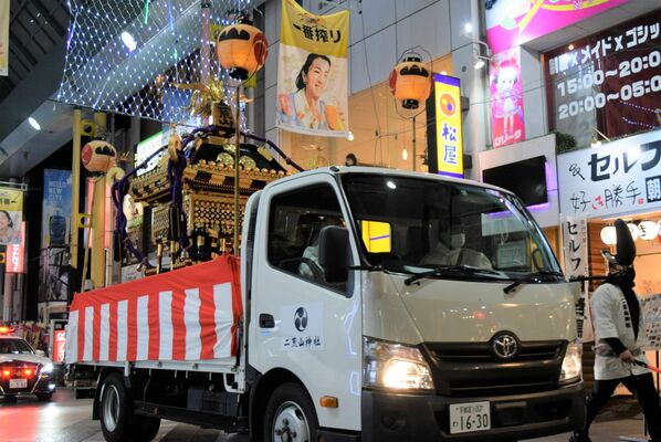 トラックでオリオン通りを渡御する神輿