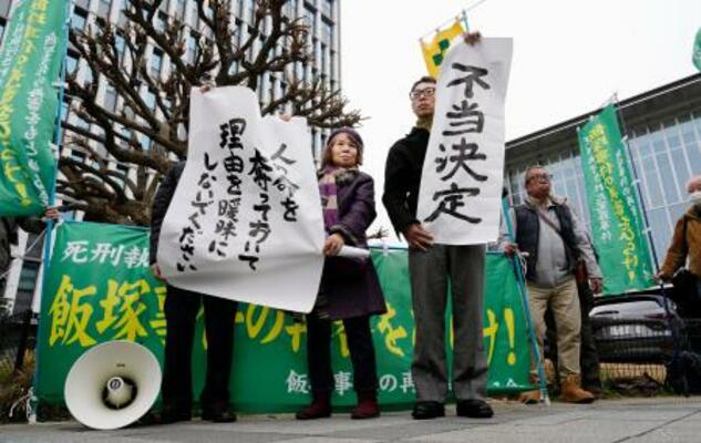「飯塚事件」の再審開始が認められず、福岡高裁前で「不当決定」などと書かれた紙を掲げる支援者ら=16日午後