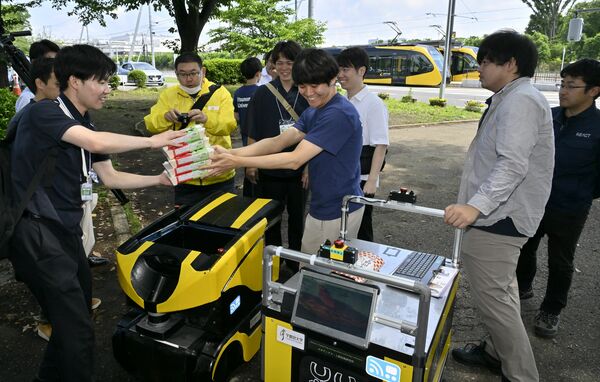 目的地のかしの森公園に到着したロボットから弁当を取り出す関係者=1日午前10時10分、芳賀町下高根沢