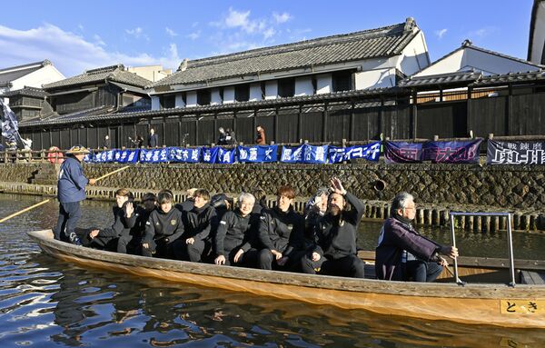 蔵が並ぶ巴波川で船上パレードする栃木シティの選手ら＝11日午後３時20分、栃木市湊町
