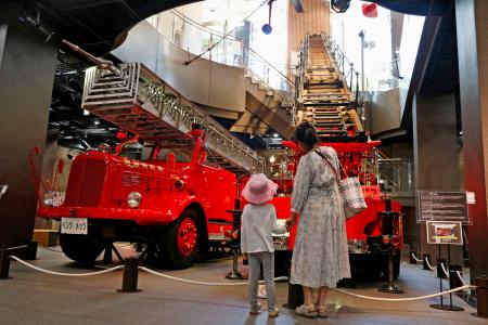 　「消防博物館」で消防車の展示を見る親子＝東京都新宿区