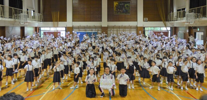 応援の旗を振る児童と山本選手（中央）