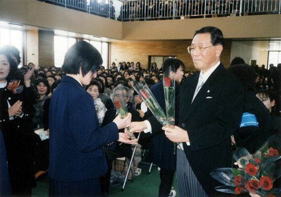 高校卒業式で生徒一人一人に、新たな門出を祝い花を手渡す須賀さん（右）＝２００７年３月