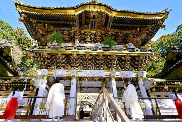 笹竹などで陽明門の汚れをはらい清める神職とみこ＝20日午前10時10分、日光市山内