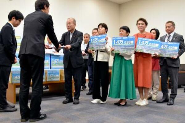 政府側(手前)に署名を渡す議連メンバーら=18日午後、国会内