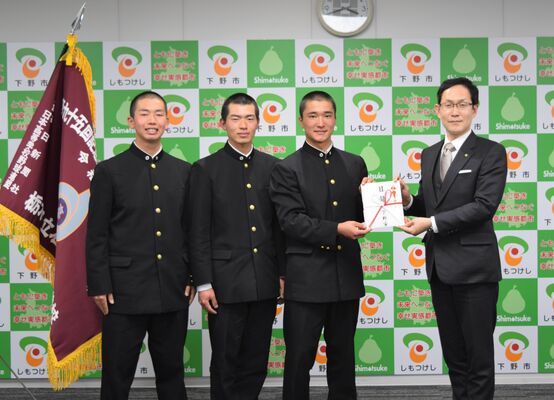 坂村市長から目録を受け取る横松主将（右から２人目）、大金副主将（同３人目）、藤巻投手（同４人目）