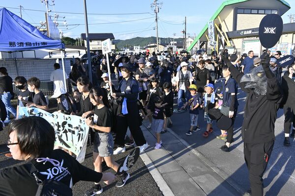 黒い装いで中心部を練り歩く行列