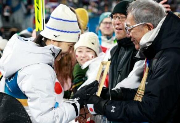　女子個人ラージヒルを終え、母信子さんの写真に触れる丸山希。右は父守さん＝プレダッツォ（共同）