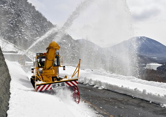 金精道路の開通に向け、路面の雪を勢いよく飛ばす除雪車＝28日午前10時10分、日光市湯元
