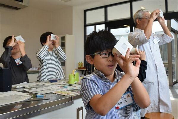 手作りの万華鏡をのぞく児童ら