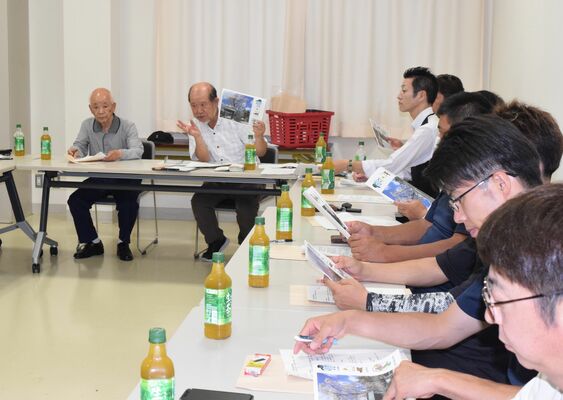 団員にカレンダー作製の意図を説明する小泉後援会長（中央）
