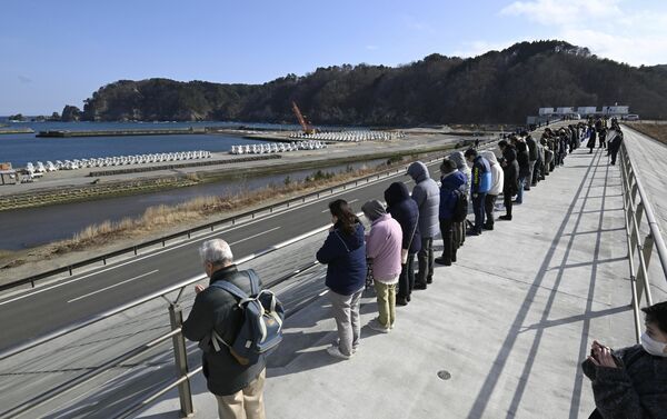 震災後造り直された高さ14・７メートルの防潮堤の上で、地震発生時刻に海に向かい黙とうする地域住民ら＝11日午後２時46分、岩手県宮古市田老川向（超広角レンズ使用）