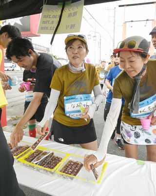 給スイーツポイントで駄菓子を手にするランナーら