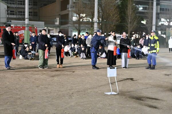 校庭に避難後、初期消火体験をする定時制生徒たち