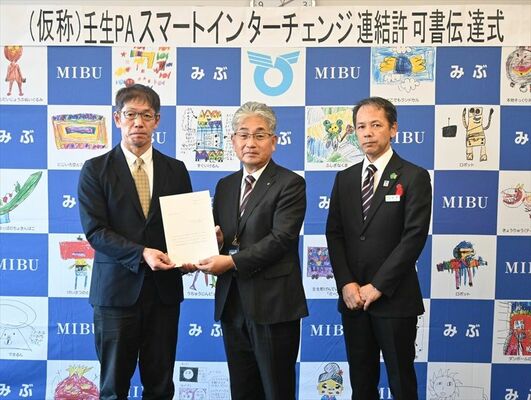 吉田所長（左）から連結許可書を受け取った小菅町長（中央）と星野所長