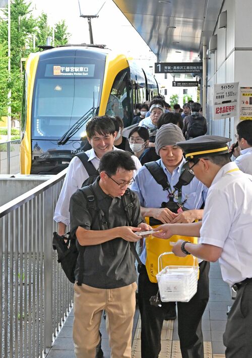 記念品を受け取るＬＲＴの利用者＝９日午後、宇都宮市宮みらい