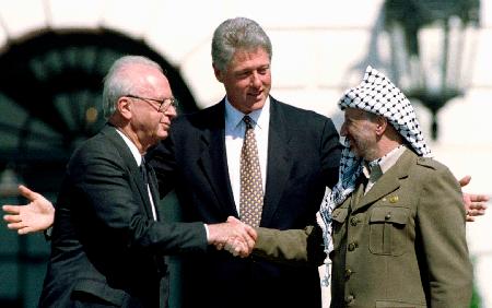 　１９９３年９月、暫定自治宣言の調印式で握手するイスラエルのラビン首相（左）とＰＬＯのアラファト議長（右）。中央はクリントン米大統領＝ワシントン（ロイター＝共同）