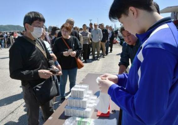 高校生が開発し、道場六三郎さんが監修したサバ缶を買い求める人たち=9日午前、鳥取県境港市